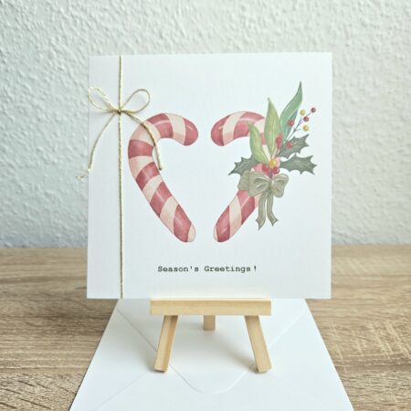 Carte deNoël artisanale Season’s Greetings avec cannes en sucre en forme de coeur, fil doré et illustration signée @pyokoo_illustration, créée par Cartes d’émoi