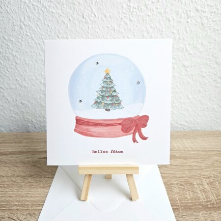 Carte de voeux illustrée représentant une boule à neige avec un sapin décoré, réalisée en collaboration avec @pyokoo_illustration, création Cartes d’émoi