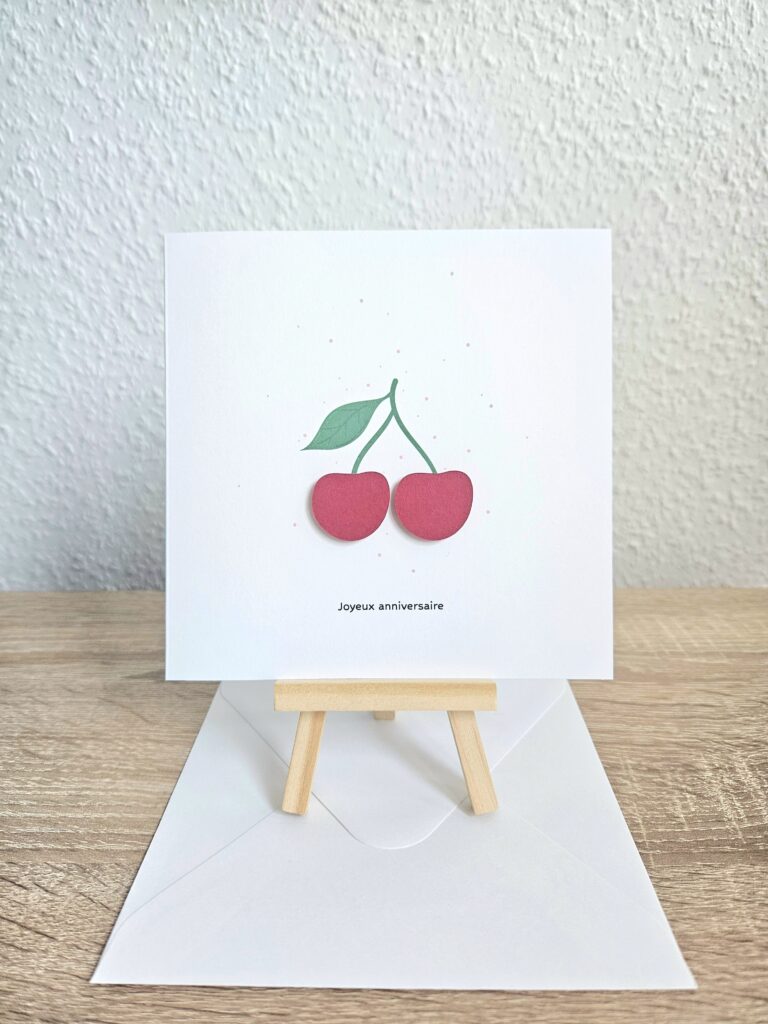 Carte d’anniversaire avec deux cerises rouges en relief et le texte "Joyeux anniversaire".