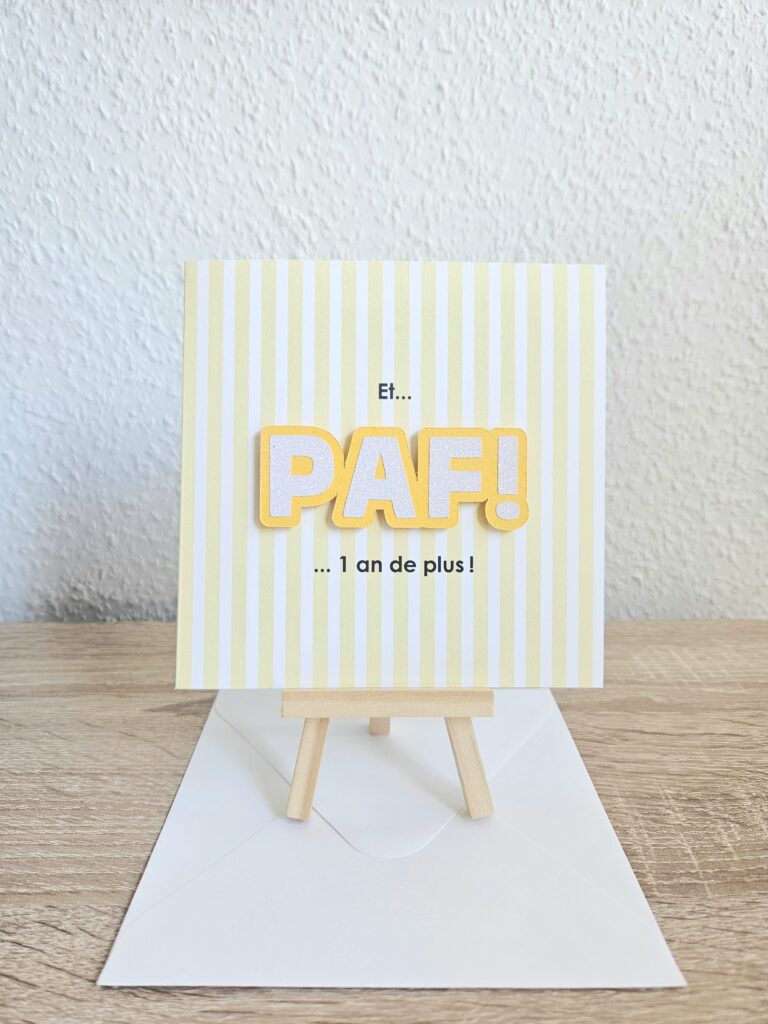 Carte d’anniversaire avec le message "Et… PAF ! 1 an de plus !" sur fond rayé jaune.
