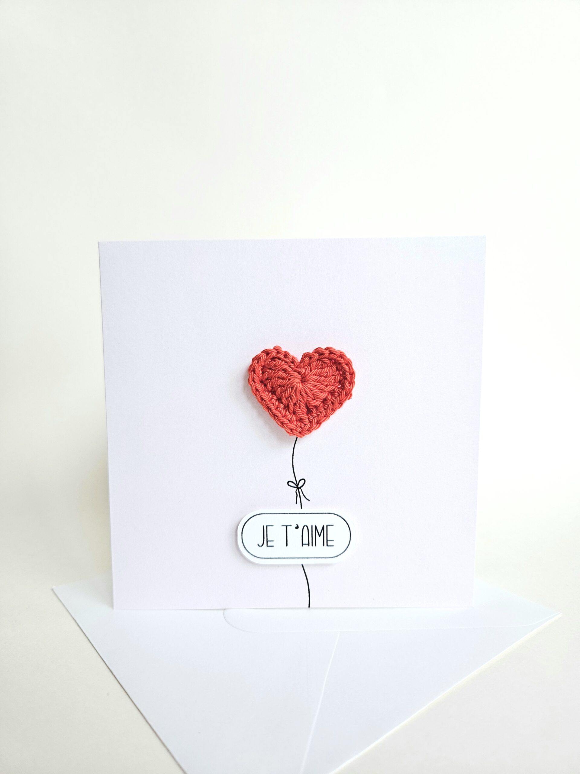 Carte d’amour minimaliste avec coeur rouge éclatant crocheté à la main en forme de ballon et message "je t’aime", coeur magnet détachable.