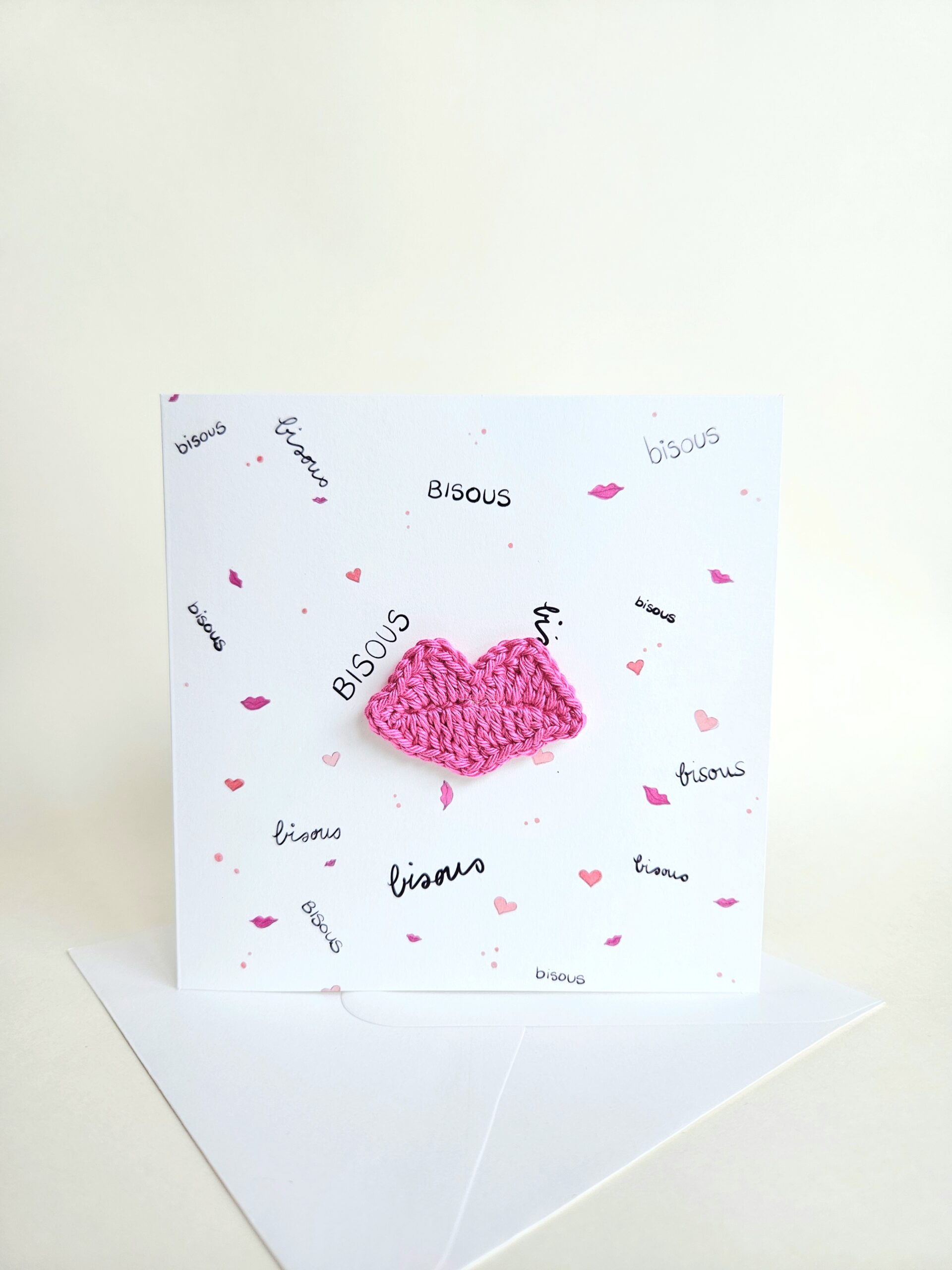Carte artisanale avec motifs bisous et coeurs, lèvres roses fuchsias crochetées à la main aimantées et détachables.
