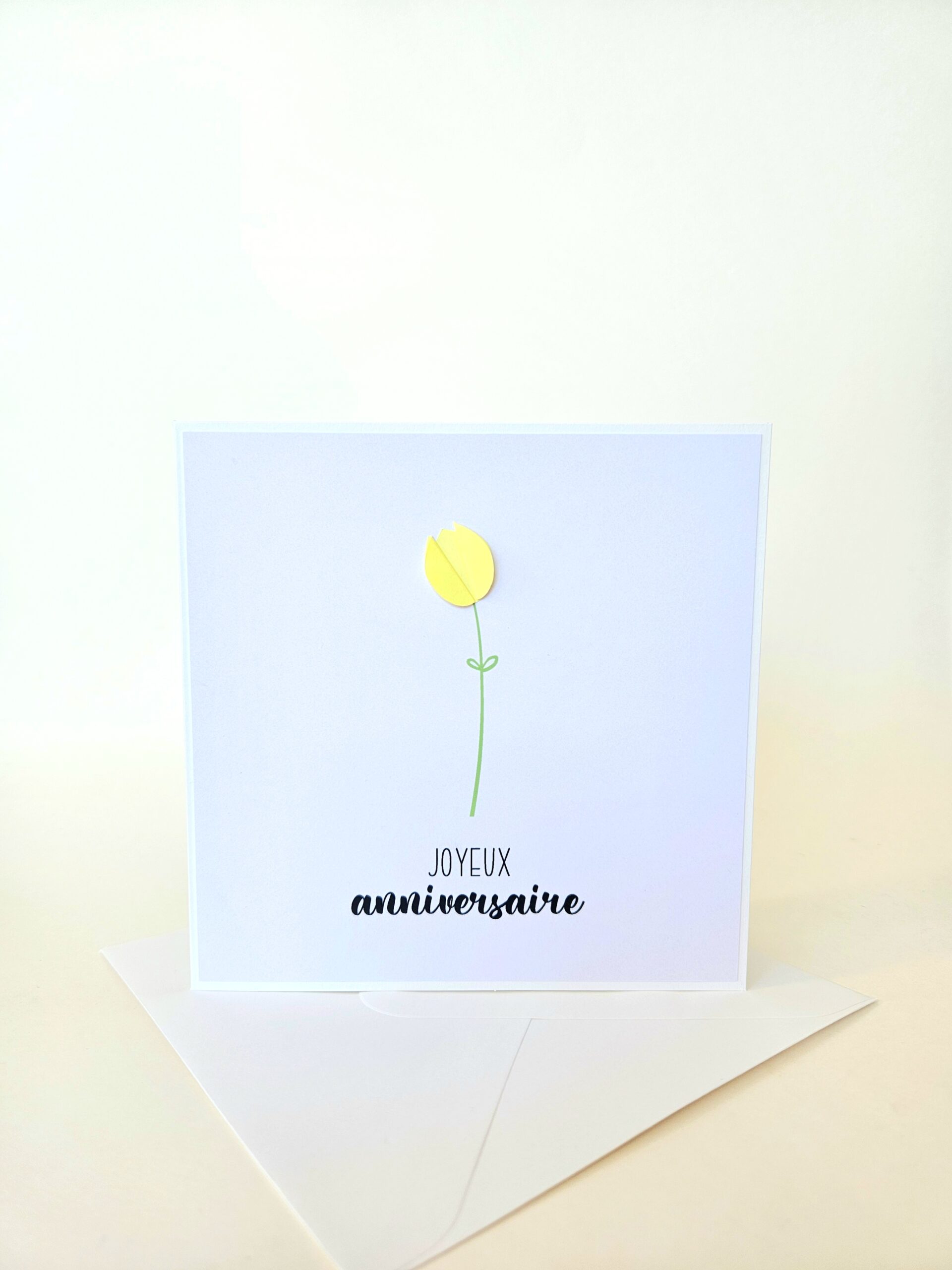 Carte d’anniversaire minimaliste avec tulipe jaune en papier en relief et message "Joyeux anniversaire".