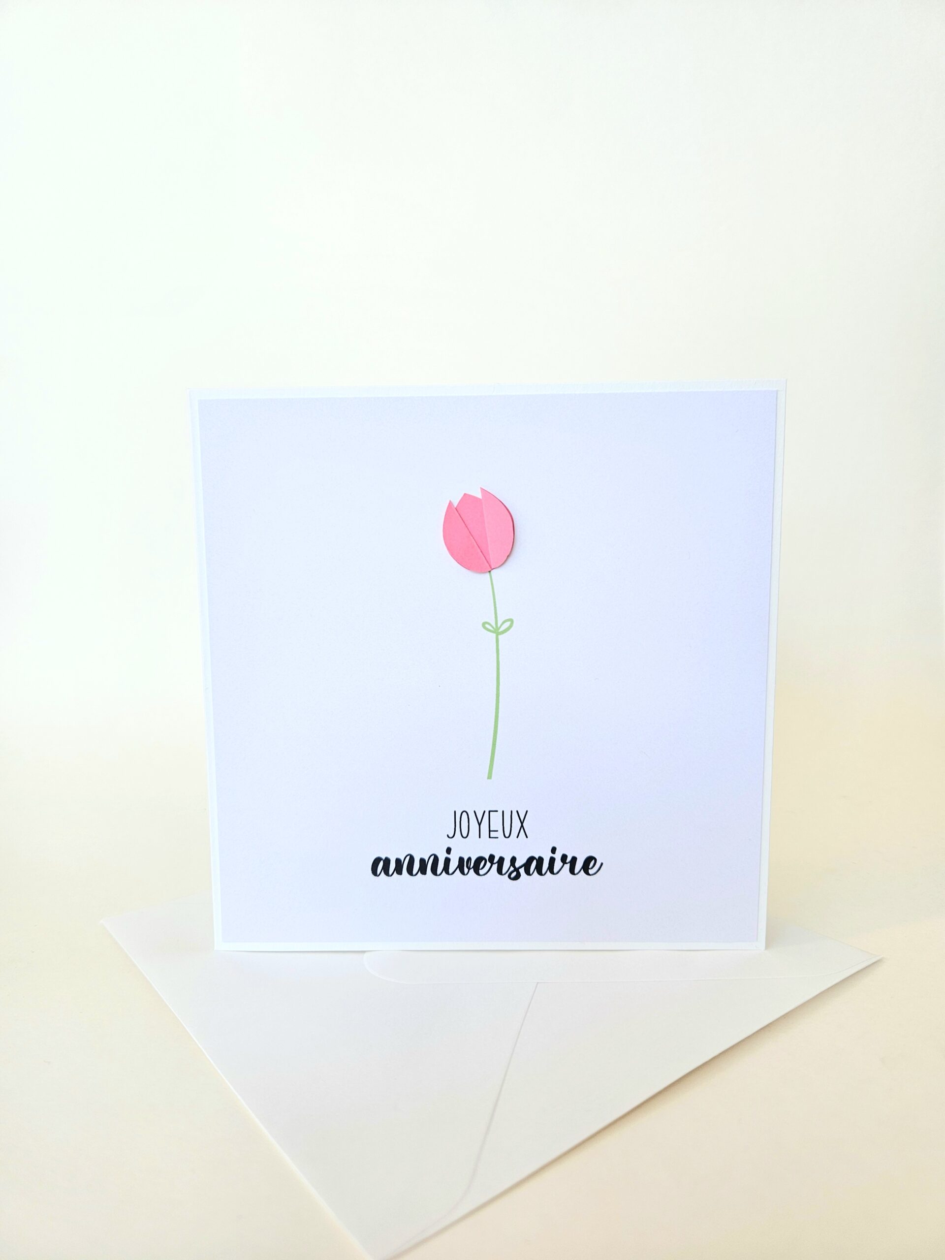 Carte d’anniversaire minimaliste avec tulipe rose en papier en relief et message "Joyeux anniversaire".