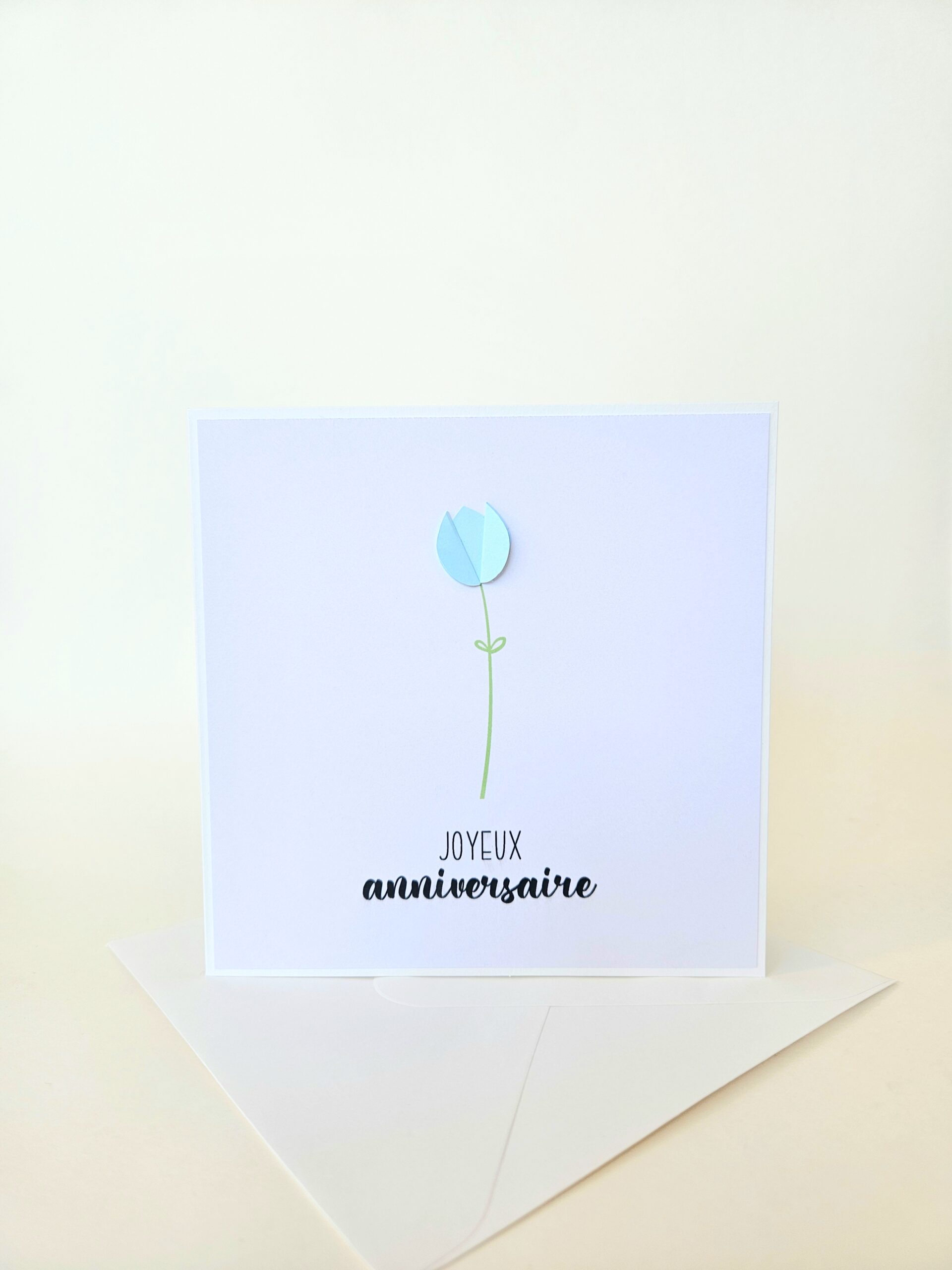 Carte d’anniversaire minimaliste avec tulipe bleue en papier en relief et message "Joyeux anniversaire".