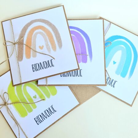Carte de naissance avec arc-en-ciel minimaliste et le message "Bienvenue", attachée avec une ficelle naturelle.