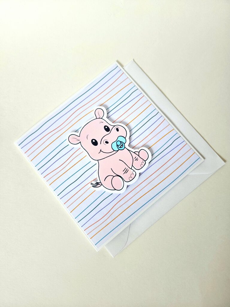 Carte de naissance avec un adorable petit hippopotame tenant une tétine sur un fond rayé pastel.
