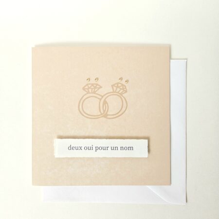 Carte de mariage avec deux alliances entrelacées et le message "deux oui pour un nom", décorée de petites perles.