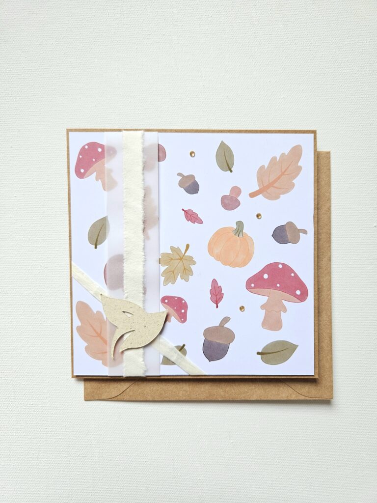 Carte d’automne artisanale décorée de champignons, feuilles, glands et citrouille.